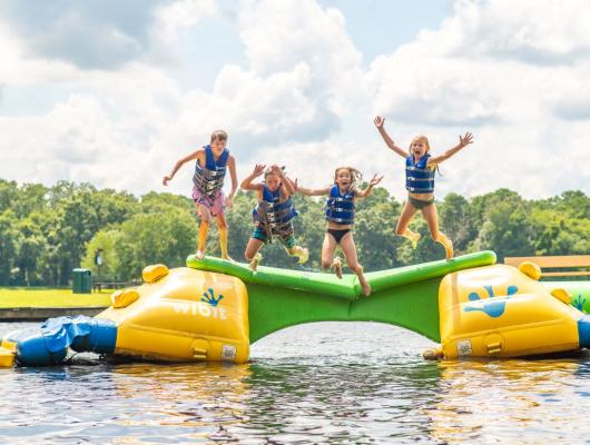 Kids jumping from inflatable water obstacle course