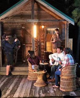 people gathered around campfire in front of cabin